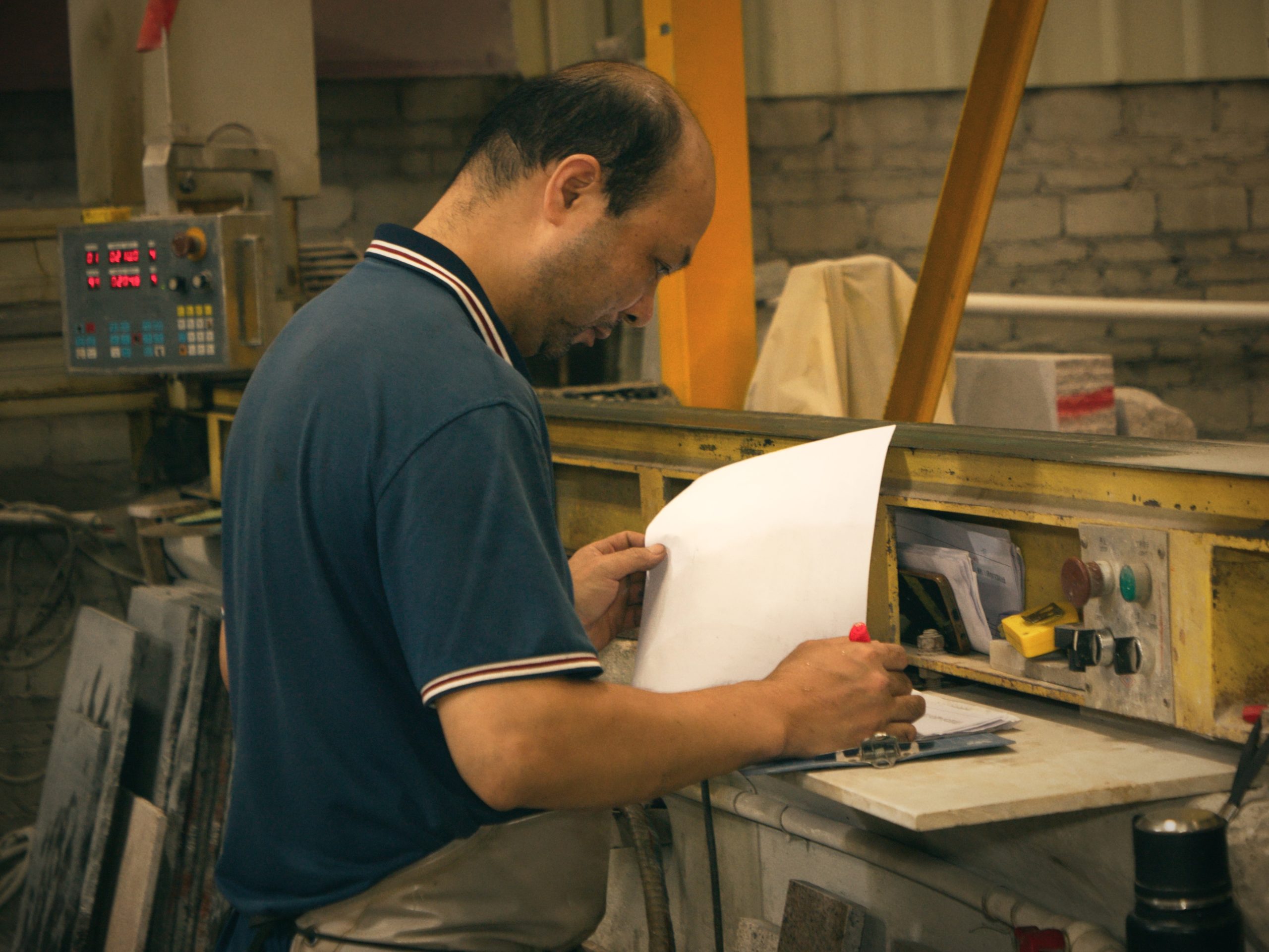 Custom stone manufacturing process: workers reviewing blueprints and technical drawings for bespoke projects
